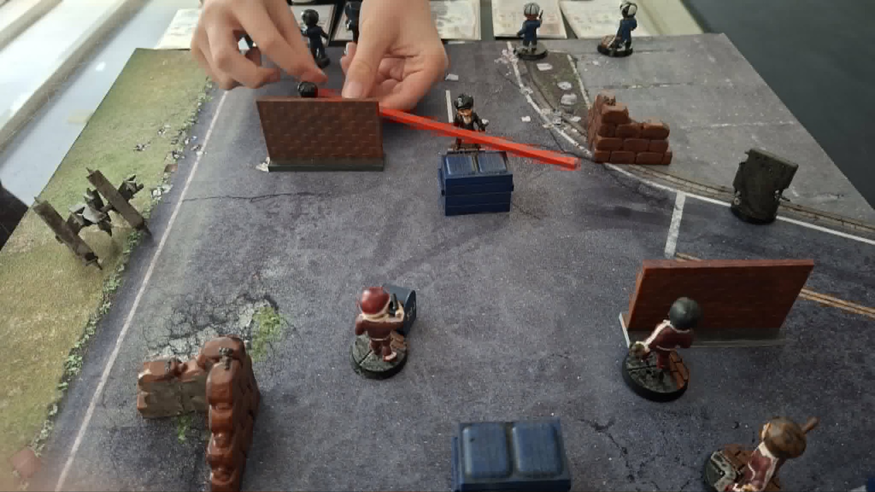 Hands moving TAP! miniatures between terrain and cover