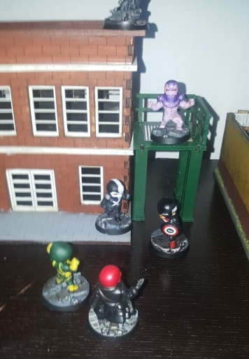 Painted miniatures fighting around a model building